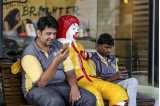 Two men on a bench with statue of Ronald McDonald