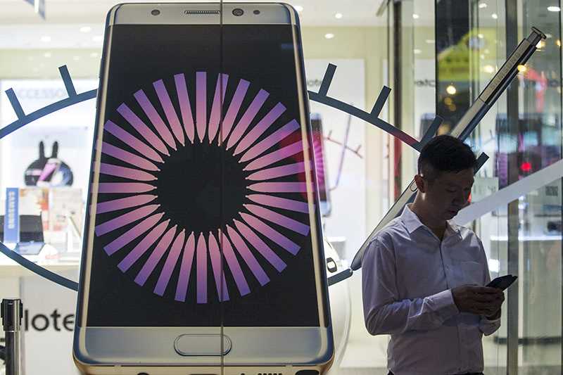 Picture of a man outside a shop window with a large mobile phone beside him