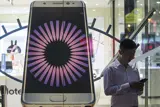 Picture of a man outside a shop window with a large mobile phone beside him