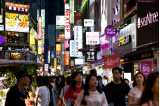 People walking down street with neon signs