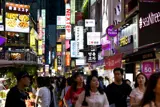 People walking down street with neon signs